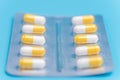 Medicine white and yellow pills packed in blisters on blue background