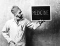 Medicine word written on blackboard which is held by doctor