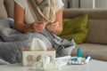 Medicines against colds and paper napkins are on the table, a woman with signs of flu and colds is sitting in the background and Royalty Free Stock Photo