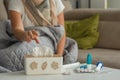 Medicines for colds and paper napkins are on the table, a woman with signs of flu and colds is sitting in the background and takes Royalty Free Stock Photo