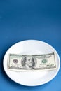 Medicines costs money. Drugs and dollars.White plate with multi-colored pills and capsules and a 100 dollar bill on a Royalty Free Stock Photo