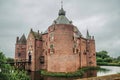 Medieval Ammersoyen Castle with its brick towers, wooden bridge, water filled moat and gardens on cloudy day.