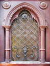Medieval arched window made of stained glass. The window is protected by an old elegant wrought-iron grating and decorated with