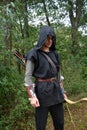 Medieval archer with black hood and coloured arrows in the quiver stands with bow Royalty Free Stock Photo