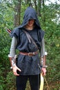 Medieval archer with black hood and coloured arrows in the quiver stands with bow