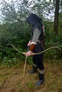 Medieval archer of the side stands with black hoodie and with tense curve and with arrow Royalty Free Stock Photo