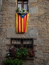 Medieval architecture stone rock building facade with Senyera flag and flower decoration, Rupit i Pruit Catalonia Spain