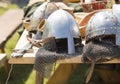 Medieval armor, helmets lie on a wooden table outdoor.