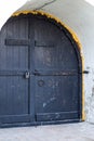 Medieval black door with metal in white wall of church Royalty Free Stock Photo