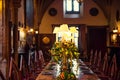 Medieval british castle interior dining table with plates, flowers and lamps. Warm light. Selective focus. copy space