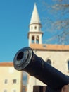 Medieval cannon in front of blurred Tower of St. John the Baptist Cathedral .in Budva in Montenegro