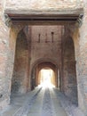 Medieval castle corridor built with bricks, full of arches, stone path that leads to the other side of the tunnel where there is Royalty Free Stock Photo