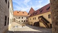 The medieval castle with towers and tiled roofs is built of stone and red brick. The courtyard is paved with stone. A staircase wi