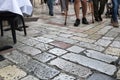 Medieval cobblestone pavement close up. Legs of tourists walking alone the ancient cobbled street.