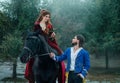 Medieval couple in love. man meets woman and gives rose in winter forest. Vintage clothing red long dress. Blue costume Royalty Free Stock Photo