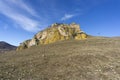 Medieval fortress on a rock. Stone walls, towers, a church, a tall metal cross. The rock is covered with yellow lichen. Bright Royalty Free Stock Photo