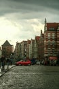 Medieval houses of the baltic architecture in the Srodmiescie district of Gdansk during a rainy sunset with pedestrians walking