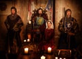 Medieval king with his queen and knights on guard in ancient castle interior Royalty Free Stock Photo