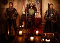 Medieval king with his queen and knights on guard in castle interior. Royalty Free Stock Photo