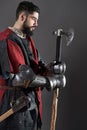 Medieval knight on grey background. Portrait of brutal dirty face warrior with chain mail armour red and black clothes