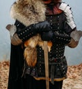 Medieval knight with sword in armor in the forest.holds the sword.by the river a man in armor, with a wolf cloak. costume games Royalty Free Stock Photo