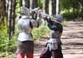 Medieval knights fight with swords in a summer forest