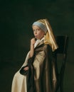 Medieval little girl as a lady with a pearl earring on dark studio background. Concept of comparison of eras, childhood