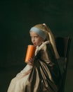 Medieval little girl as a lady with a pearl earring on dark studio background. Concept of comparison of eras, childhood