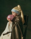 Medieval little girl as a lady with a pearl earring on dark studio background. Concept of comparison of eras, childhood