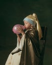 Medieval little girl as a lady with a pearl earring on dark studio background. Concept of comparison of eras, childhood