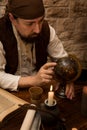 Medieval man pointing at a old globe, concept travelling and tourism