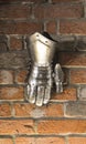 Medieval metal glove, detail of part of ancient armor, detail of war. Shining iron glove against the brick wall background Royalty Free Stock Photo