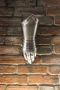 Medieval metal glove, detail of part of ancient armor, detail of war. Shining iron glove against the brick wall background Royalty Free Stock Photo