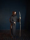 Medieval monk in robe with hood rests on a stick Royalty Free Stock Photo