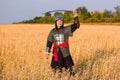 A medieval nomad warrior in oriental armor on the background of a wheat field. Standing in a fencing rack Royalty Free Stock Photo