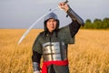 A medieval nomad warrior in oriental armor on the background of a wheat field. Standing in a fencing rack Royalty Free Stock Photo