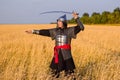 A medieval nomad warrior in oriental armor on the background of a wheat field. Standing in a fencing rack Royalty Free Stock Photo