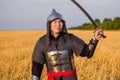 A medieval nomad warrior in oriental armor on the background of a wheat field. Standing in a fencing rack Royalty Free Stock Photo