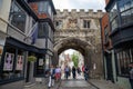 The medieval North Gate, known as the High Street Gate, to the Cathedral Close. Tourists walk along High Street, leading to