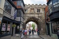 The medieval North Gate, known as the High Street Gate, to the Cathedral Close. Tourists walk along High Street, leading