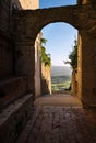 Medieval old town narrow street with an antique arch with a picturesque Tuscany hills landscape view in Pienza, Province of Siena Royalty Free Stock Photo