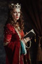 medieval queen in red dress with book, rosary and crown