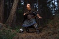 Medieval red-haired viking warrior with beard with two axes is preparing to attack on forest path