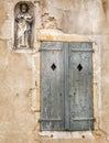 Medieval religious statue in wall alcove and weathered wooden shutters in Semur en Auxois, France