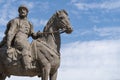 Medieval Russian prince on horseback. Close-up stone sculpture against the backdrop of a beautiful blue sky with clouds