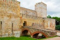 Medieval Stone Castle with Arched Bridge and Battlements Under Cloudy Sky Surrounded by Greenery, Showcasing Rustic Architecture Royalty Free Stock Photo