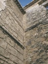 Low angle view of old medieval stone facade corner. Walls and facades background. Medieval stone cladding pattern