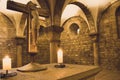 Medieval stone cross with candles in medieval church. Interior of ancient crypt. Ancient statue of Jesus Christ.