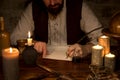 Medieval table with candles and a scroll, man writes with quill and ink Royalty Free Stock Photo