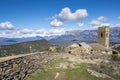 Medieval walled village in ruins with a crenelated tower and snow-capped mountains in the background